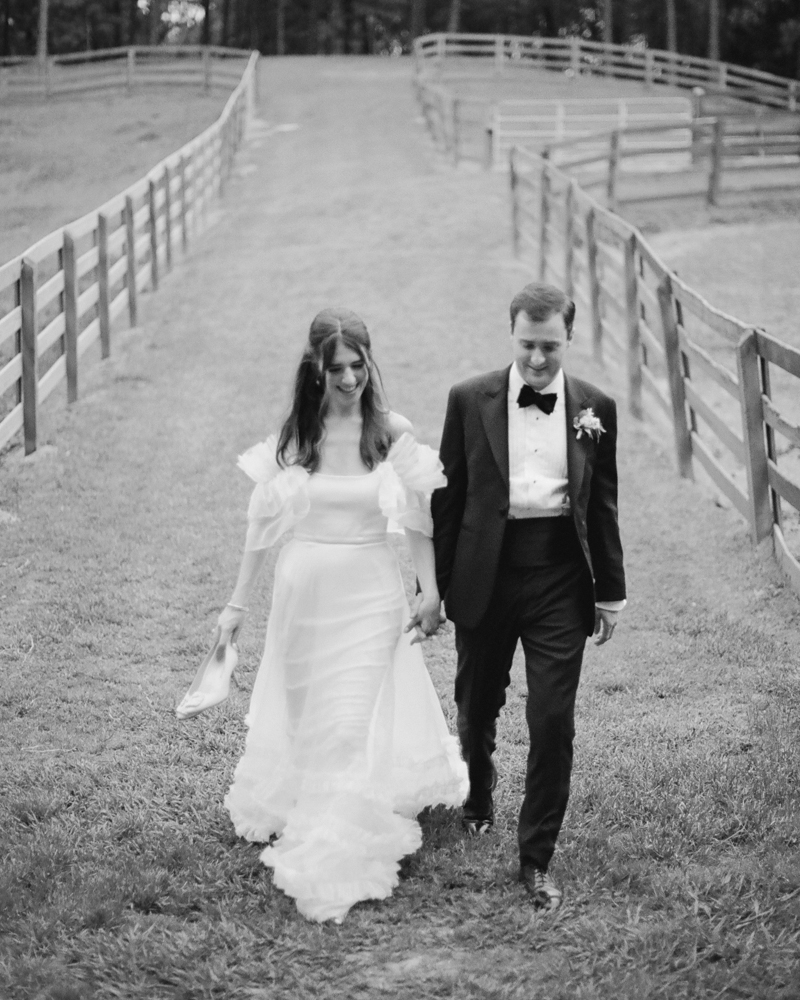 The bride and groom walk together across the equestrian estate in Alabama.