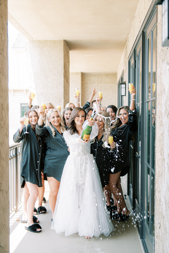 The bridal party celebrate the wedding day with a bottle of champagne on the suite balcony of Ross Bridge Resort in Alabama.