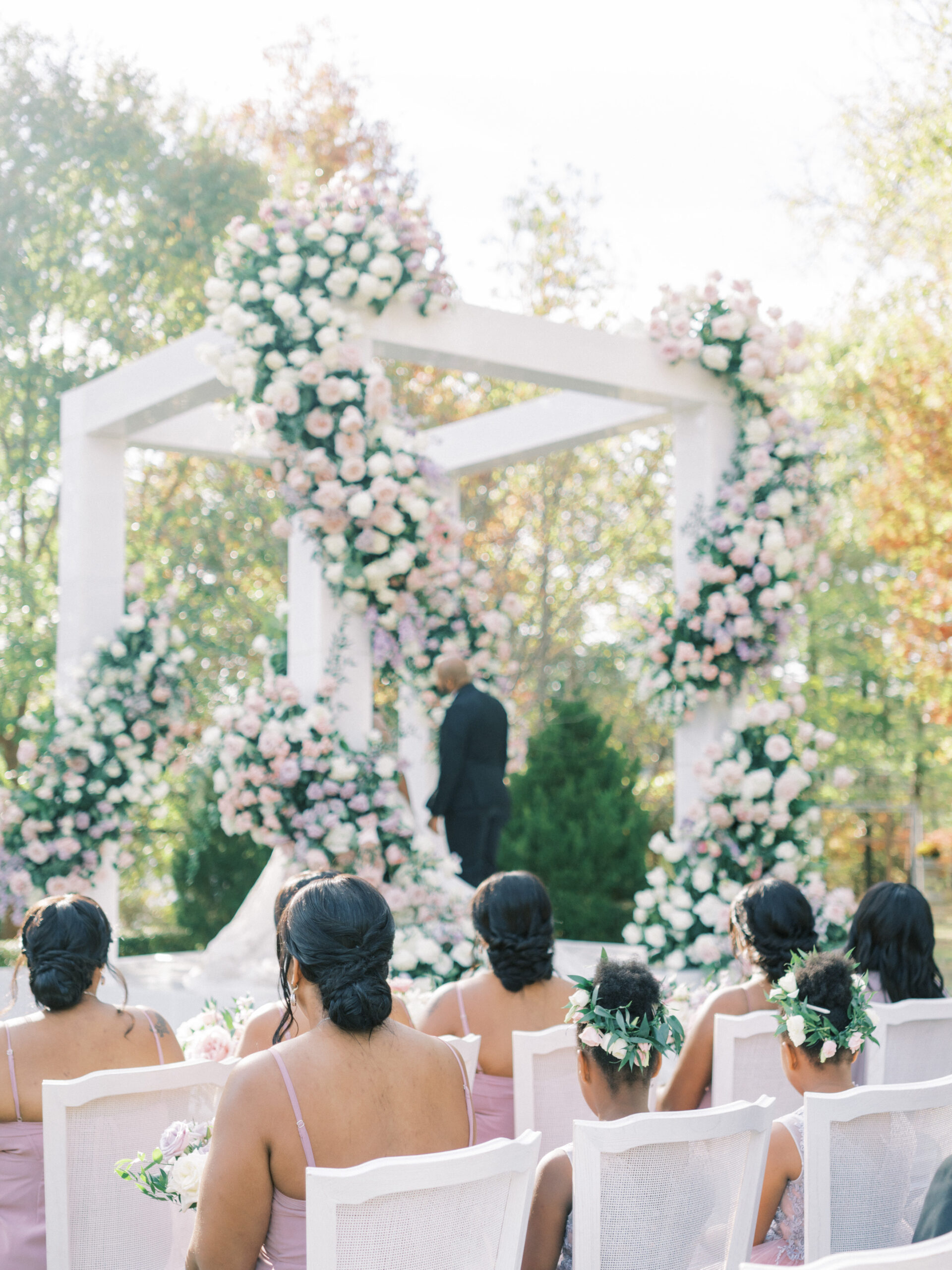 The bridal party watches the wedding ceremony decorated with many flowers.