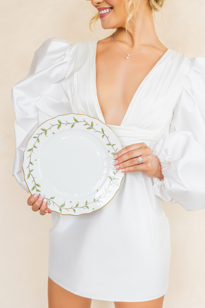 A bride holds a plate while wearing a short wedding dress from Bella's Bridal.