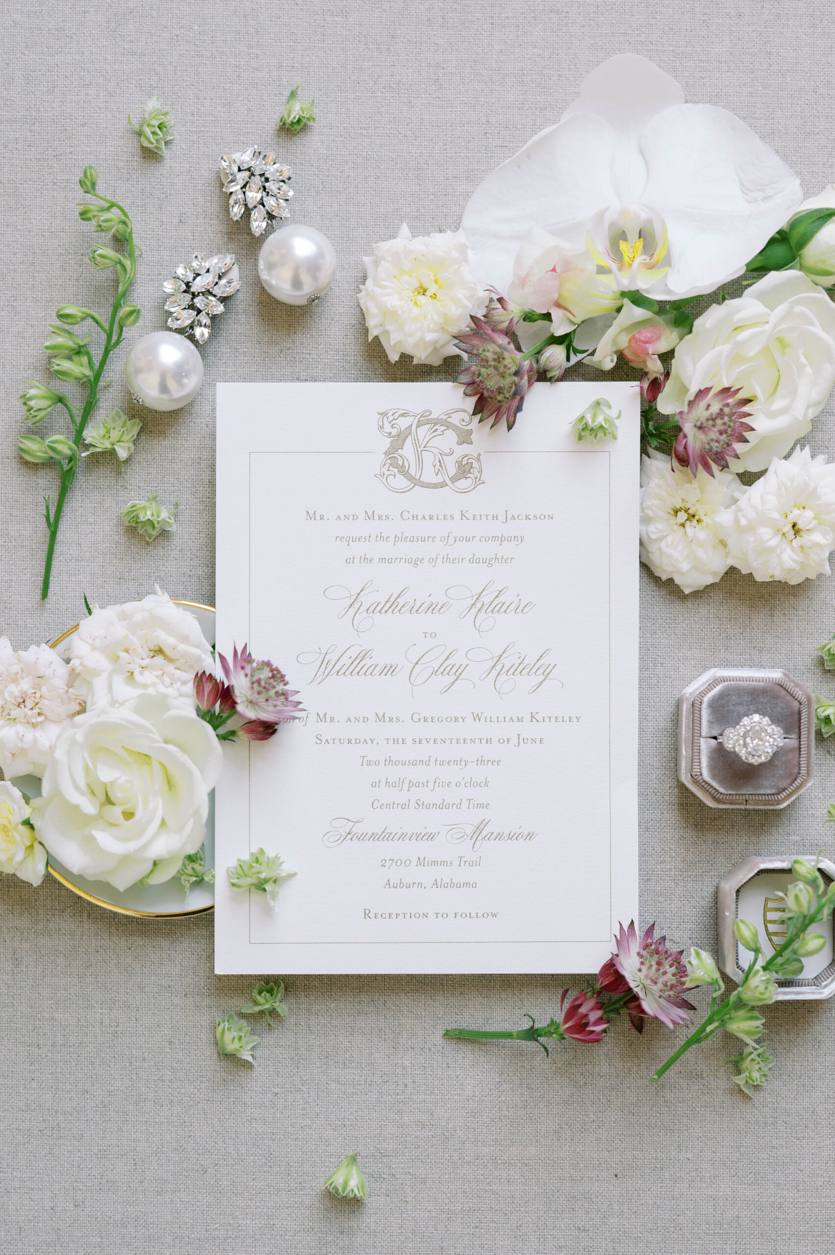 The wedding invitation is photographed with the jewelry and flowers.