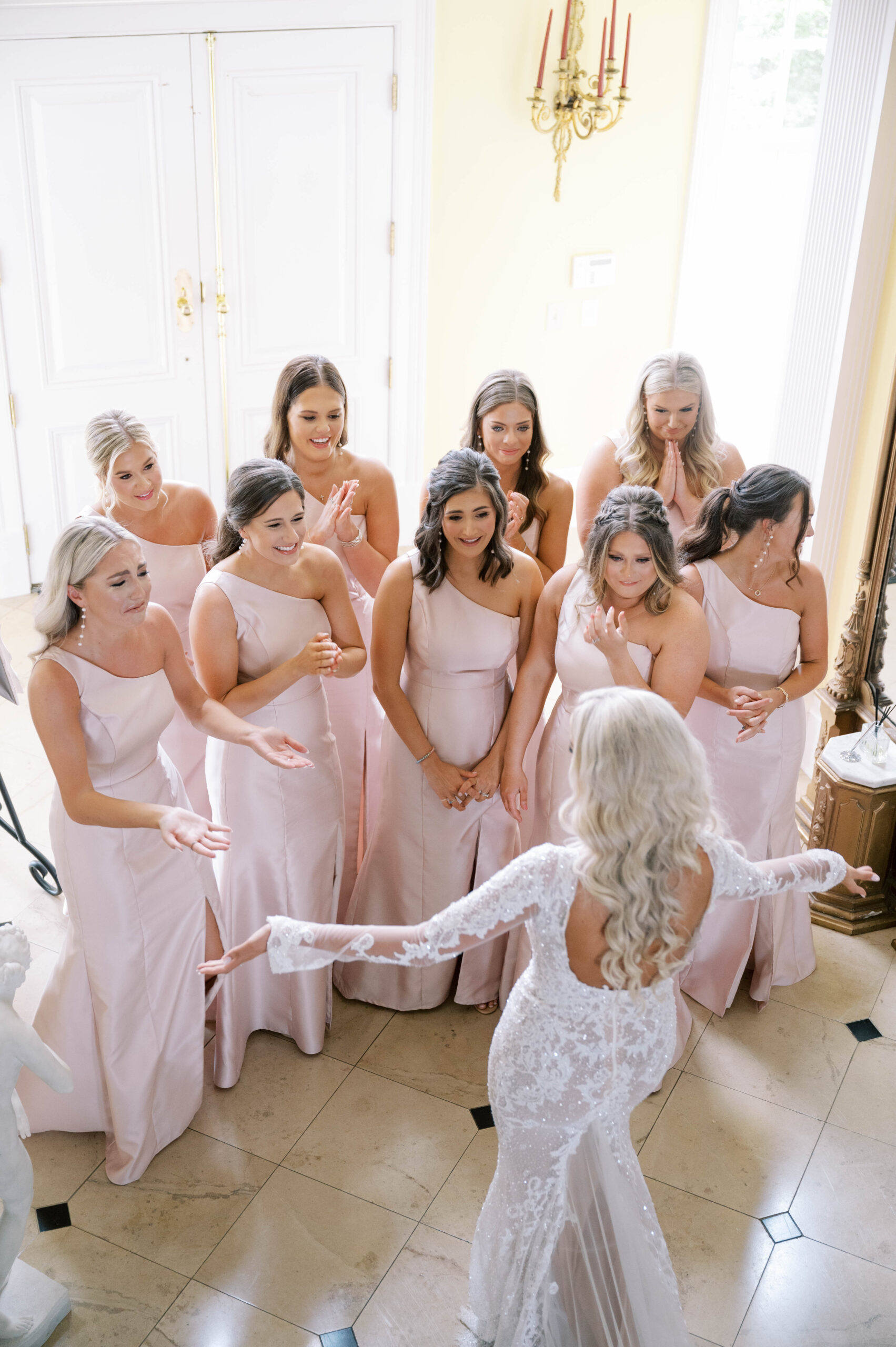 The bride surprises her bridesmaids with her wedding dress.