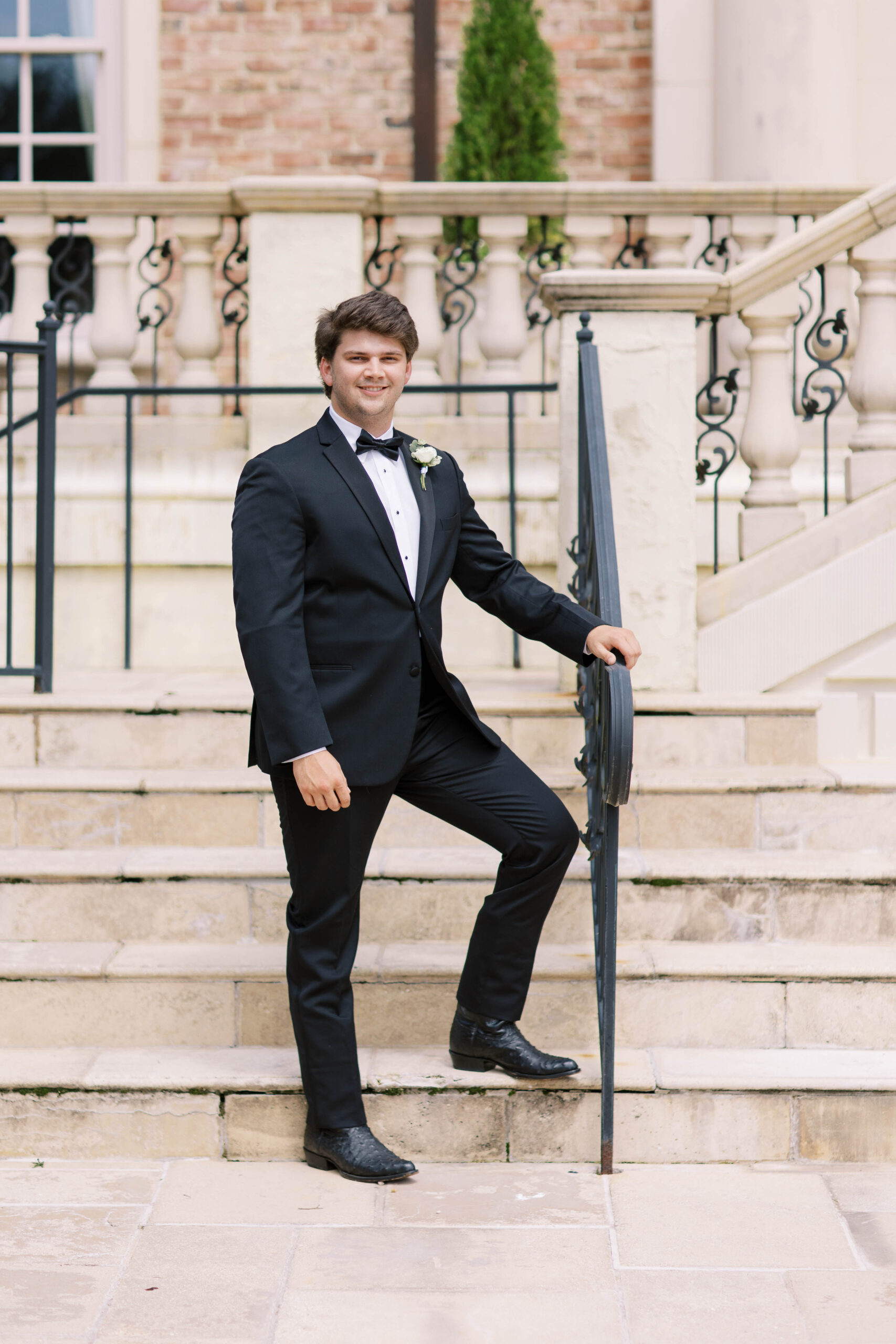 The groom stands outside on the steps before his Southern wedding ceremony.