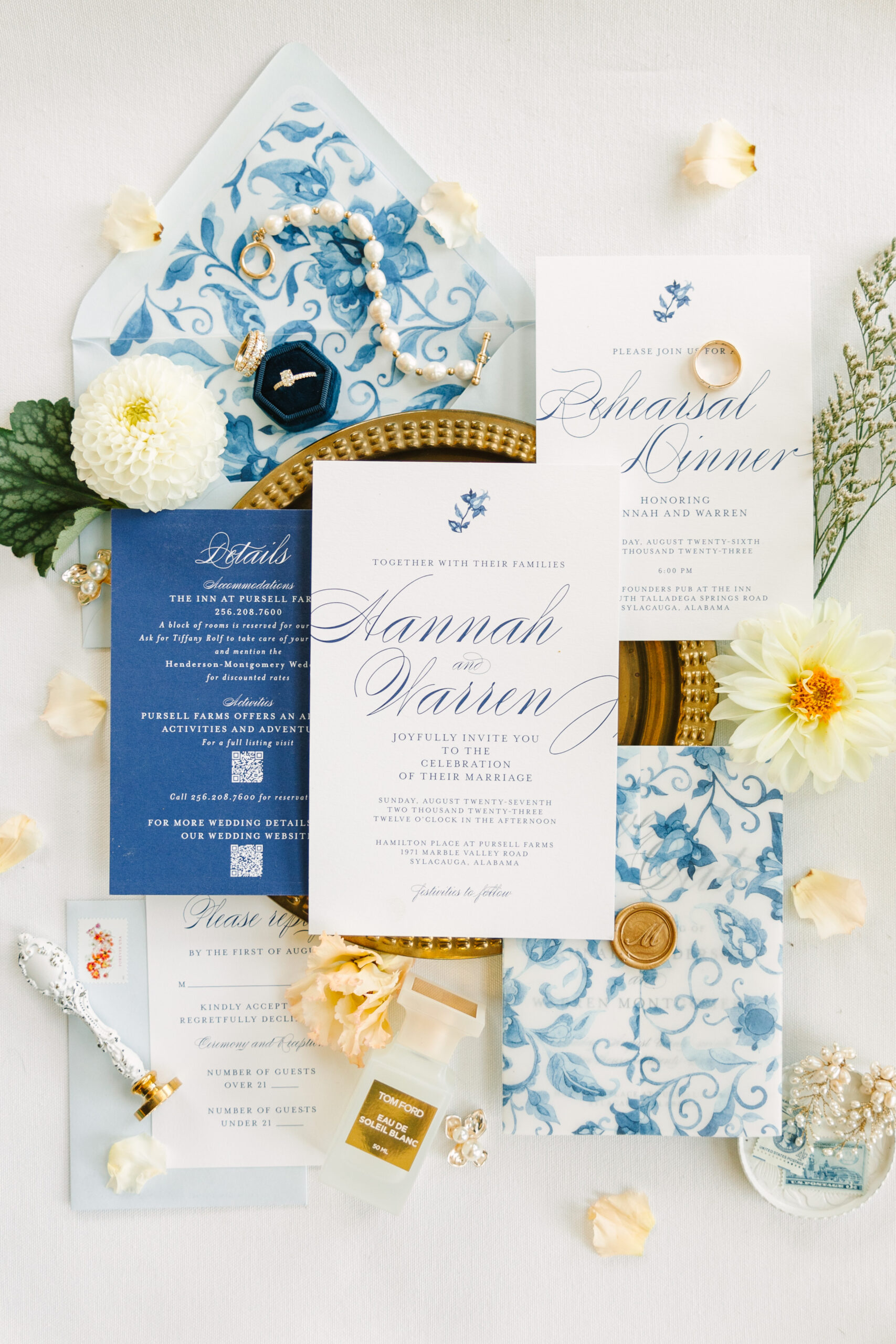 The blue and white wedding stationery is styled in a lay flat with the jewelry.