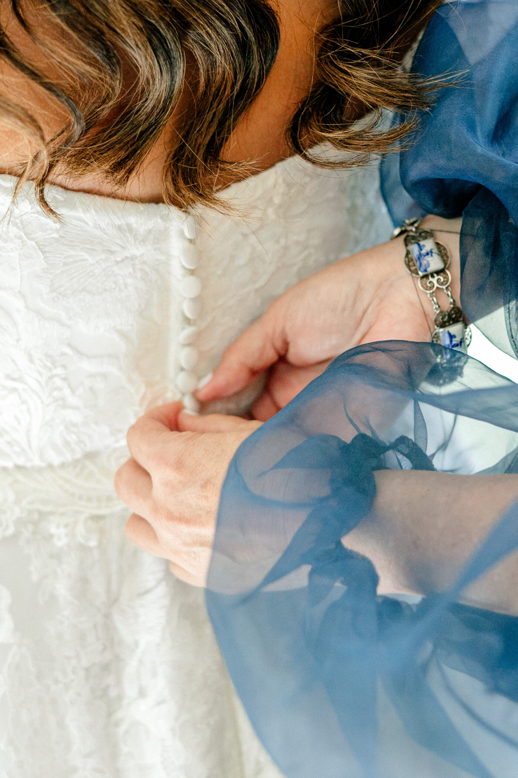 The mother of the bride buttons up her daughter's wedding dress.