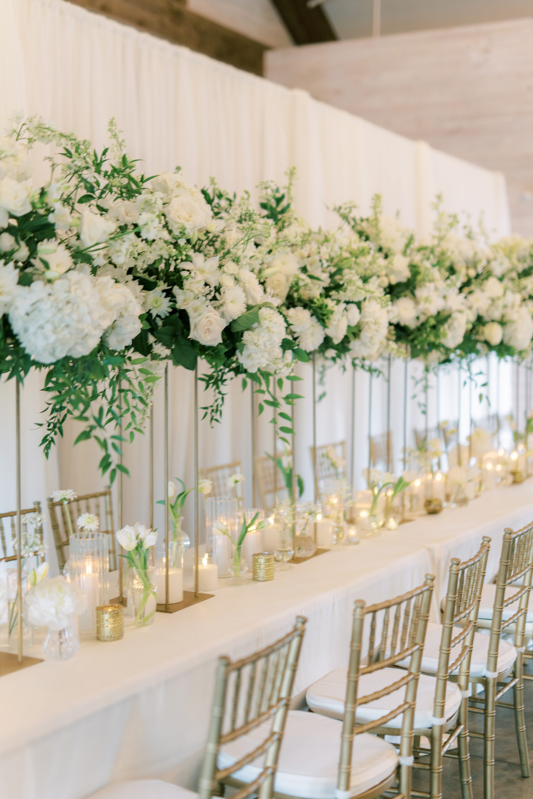 The reception table is decorated with white flowers and candles at Park Crest Event Facility.