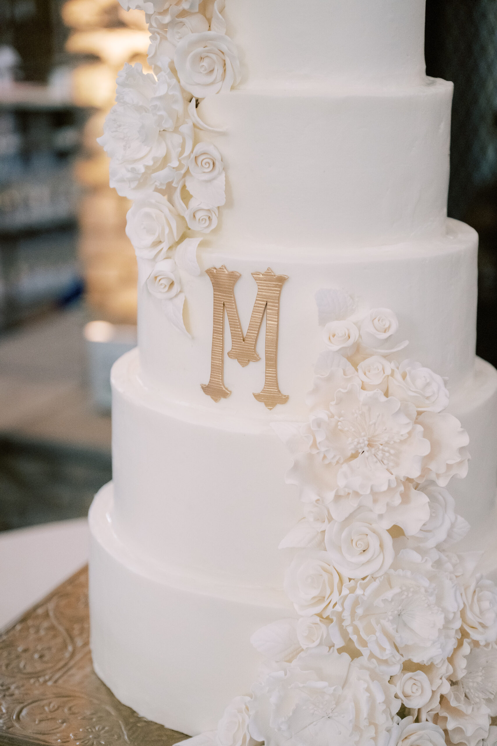 The white wedding cake has a gold monogram.