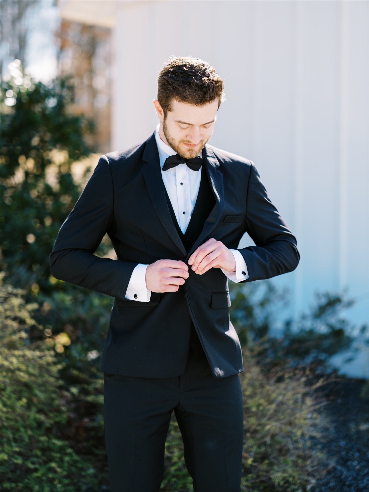 The groom buttons his tuxedo jacket before his Alabama wedding ceremony.