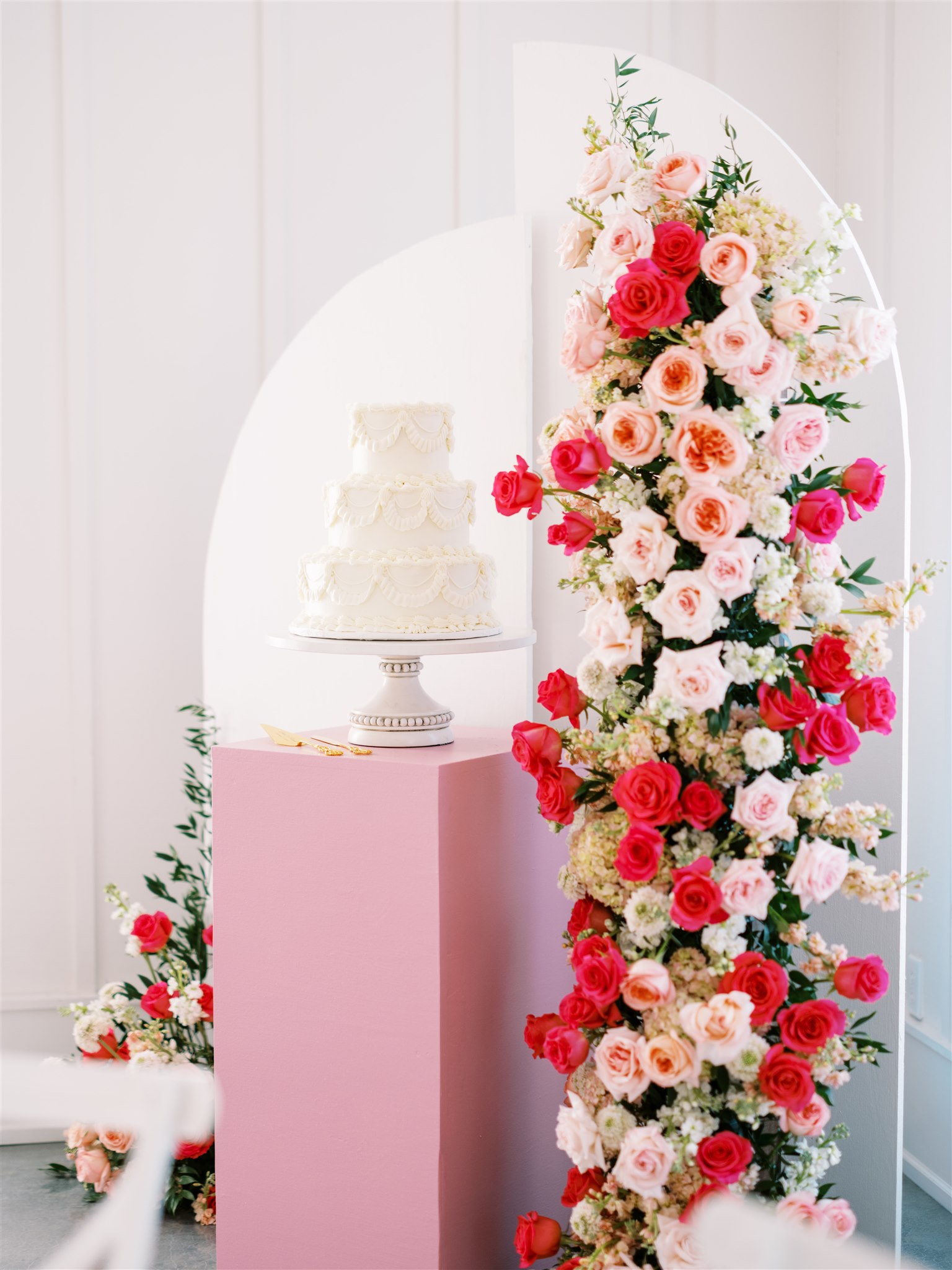 The vintage design wedding cake is styled with pink flowers at Oak Meadow Event Center.