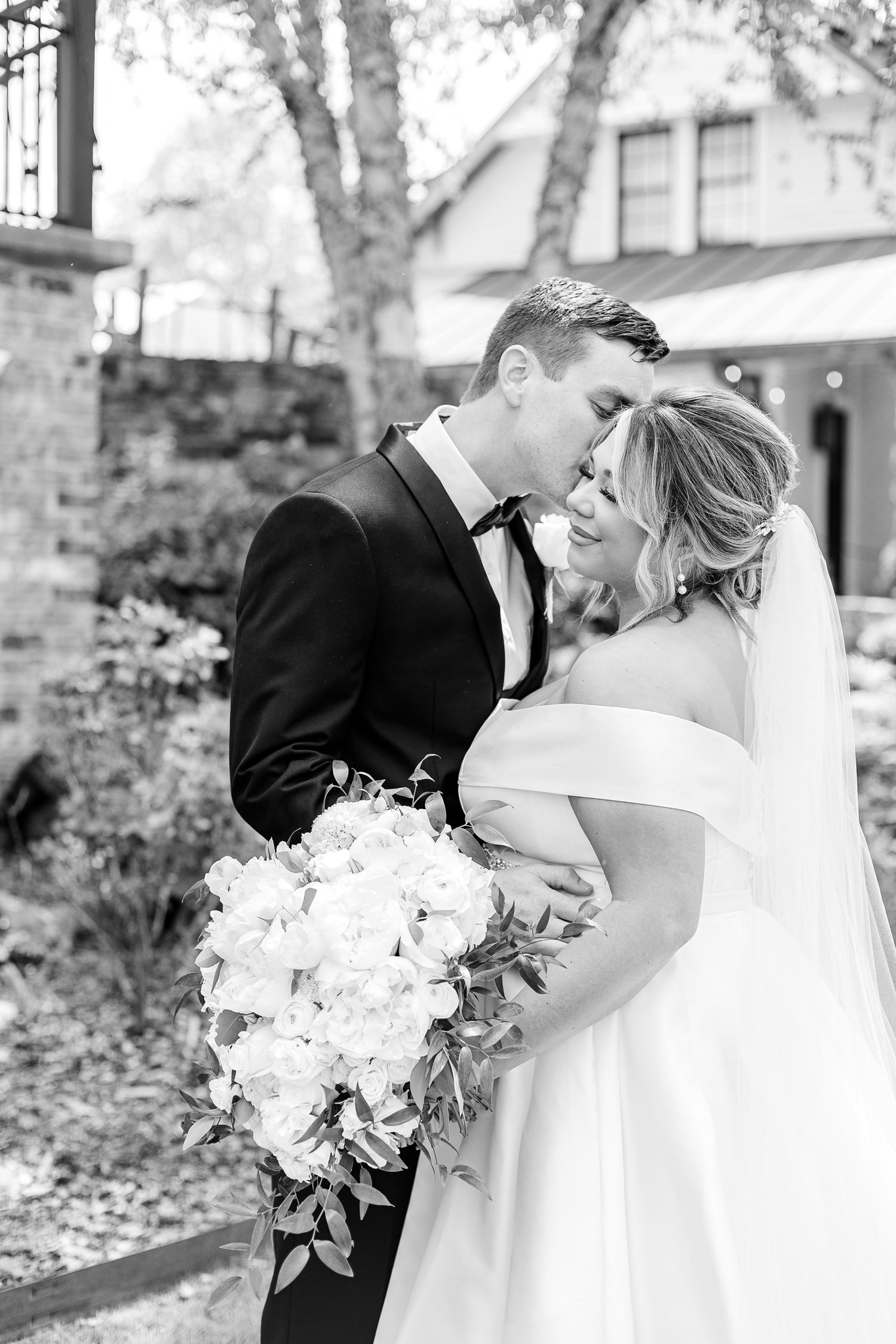 The groom kisses the bride's cheek on their wedding day in Alabama.