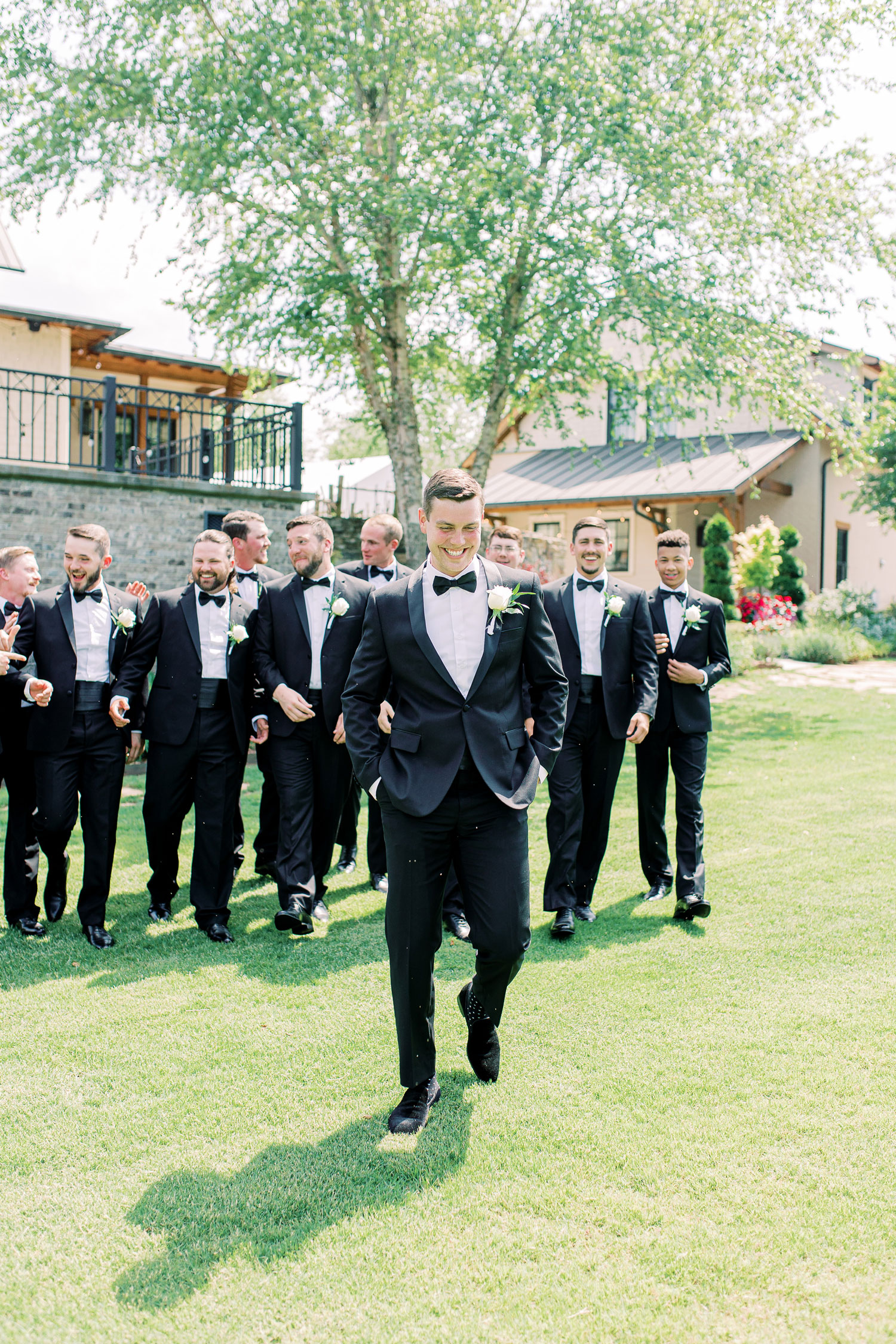 The groom and groomsmen laugh as they walk across the lawn in Alabama.