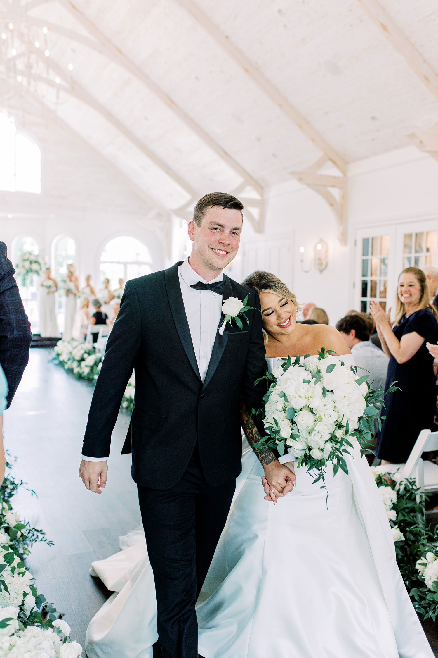 The bride leans on the groom's shoulder as they exit their wedding ceremony in Florence, Alabama.