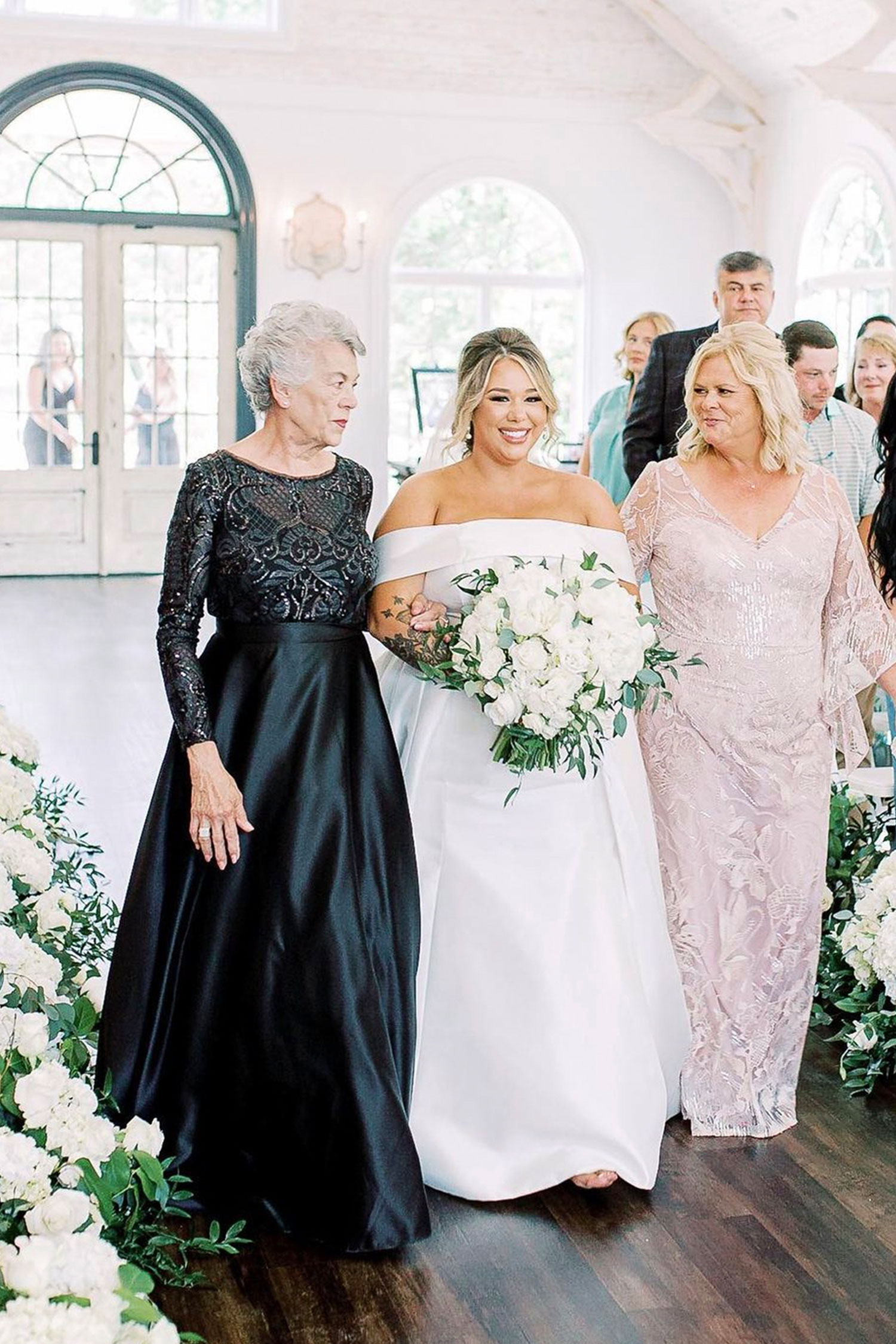 The mother and grandmother of the bride walk her down the aisle for the wedding ceremony in Florence, Alabama.