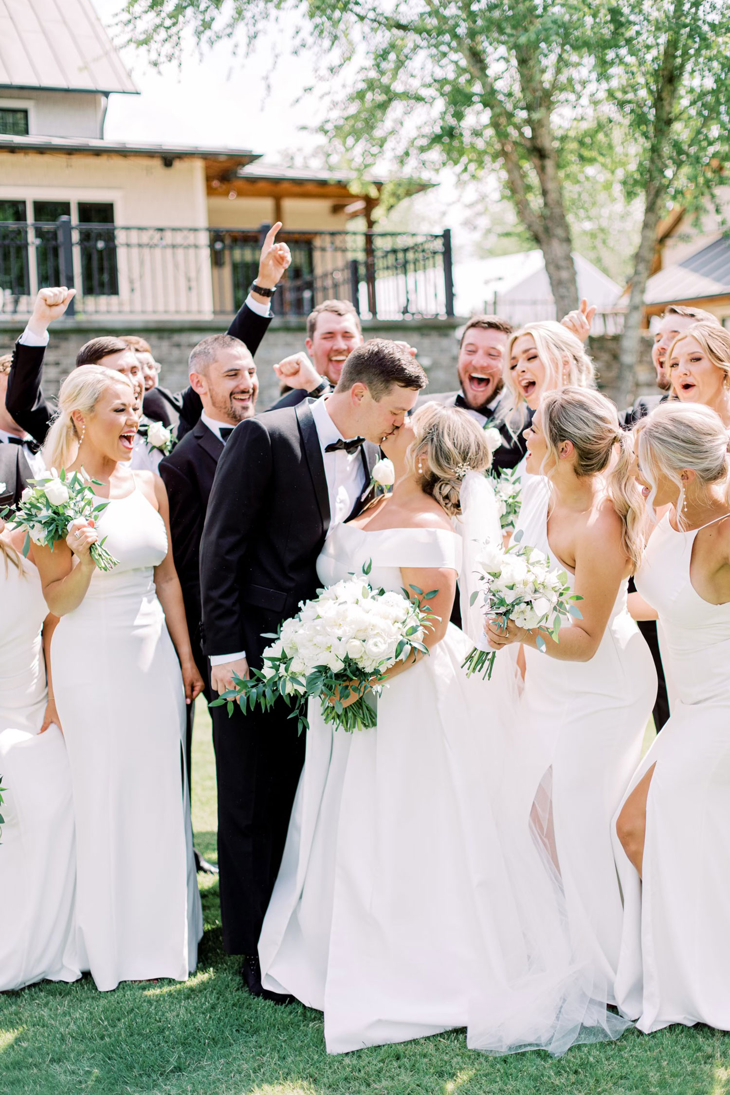 The bride and groom kiss as the wedding party cheers them on in Alabama.