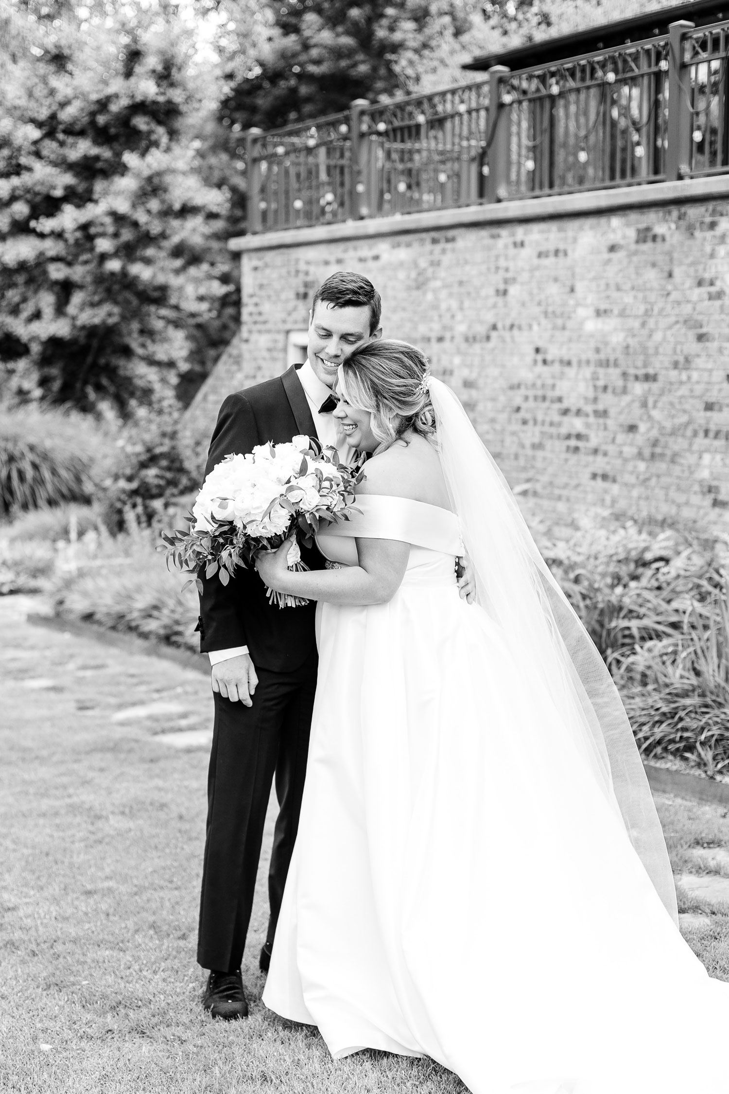 The bride and groom embrace as she holds her white flower bouquet before the wedding in Alabama.